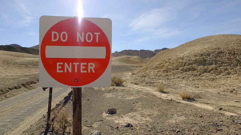A 'Do Not Enter' sign in a desolate desert setting under a bright sky.
