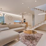 Contemporary living room with neutral tones, a sleek sofa, and elegant wooden staircase.